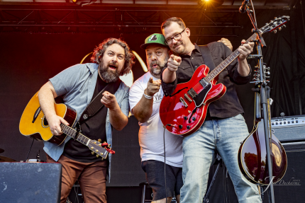 3 hommes sur scène avec des guitares